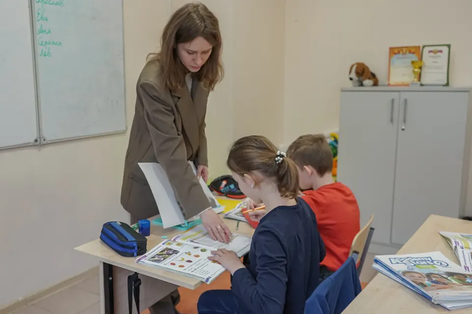Педагог помогает ученикам на занятии английского языка