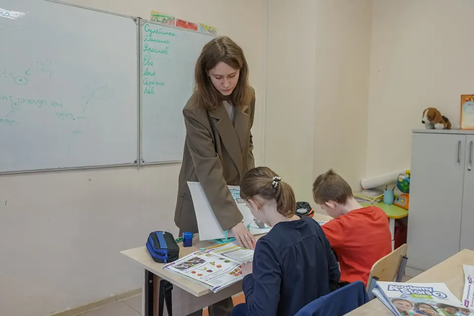 Педагог помогает ученикам на занятии английского языка